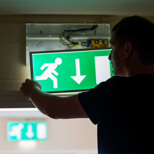 Emergency lighting engineer exposing wiring on an emergency light