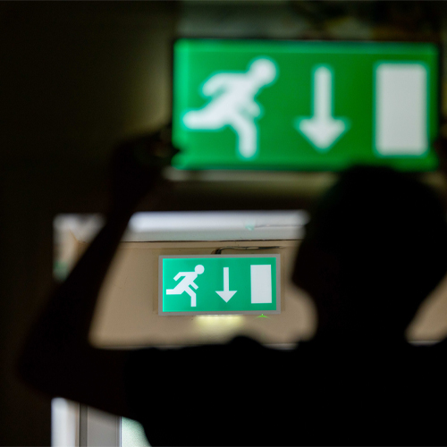 Emergency lighting engineer lifting down an emergency light Emergency lighting engineer lifting down an emergency light